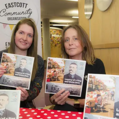 A press photo of freelance graphic designer Kate Parsons at Swindon Central Library holding the book that she wrote and designed