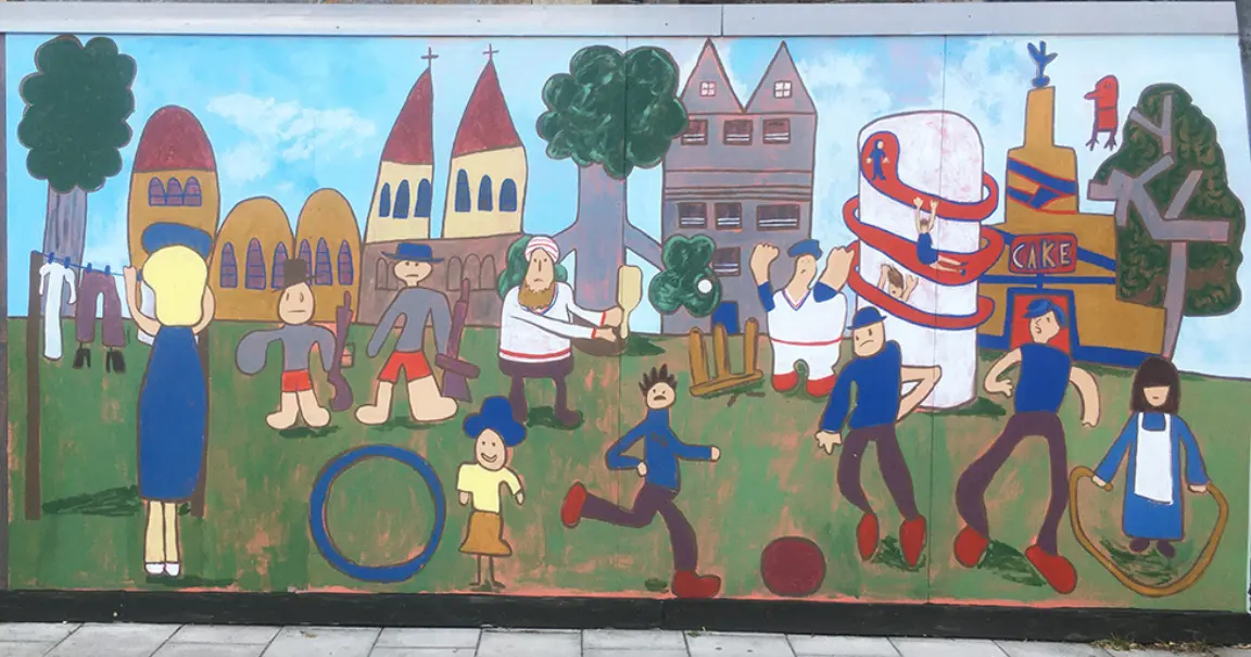 Photo of mural designed by Kate Parsons with drawings from pupils at Bridlewood Primary School in Swindon. It depicts people enaged in activties in the Victorian era in GWR Park, formerly Faringdon Road Park, and children's drawings of buildings